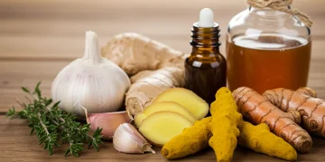 Assortment of natural antibiotics like garlic, ginger, turmeric, and thyme on wood
